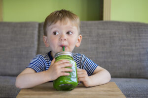 Little boy drinking a green smoothie